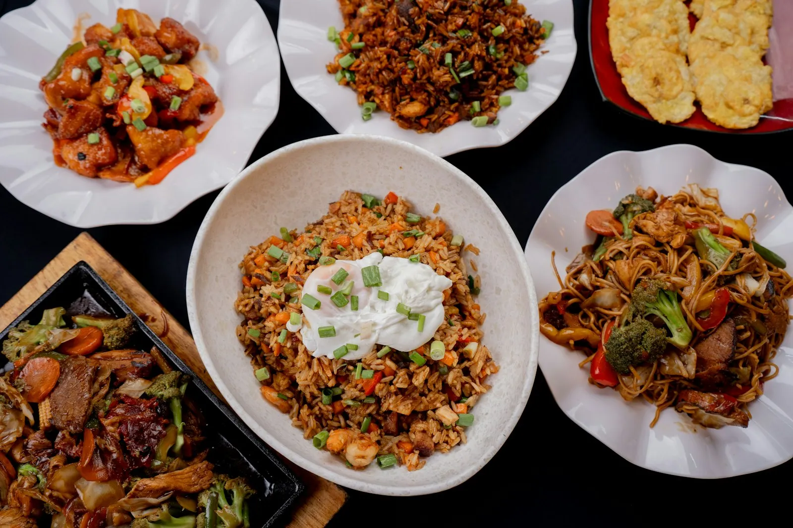 Table of assorted plates with fried rice, noodles and stir-fried dishes
