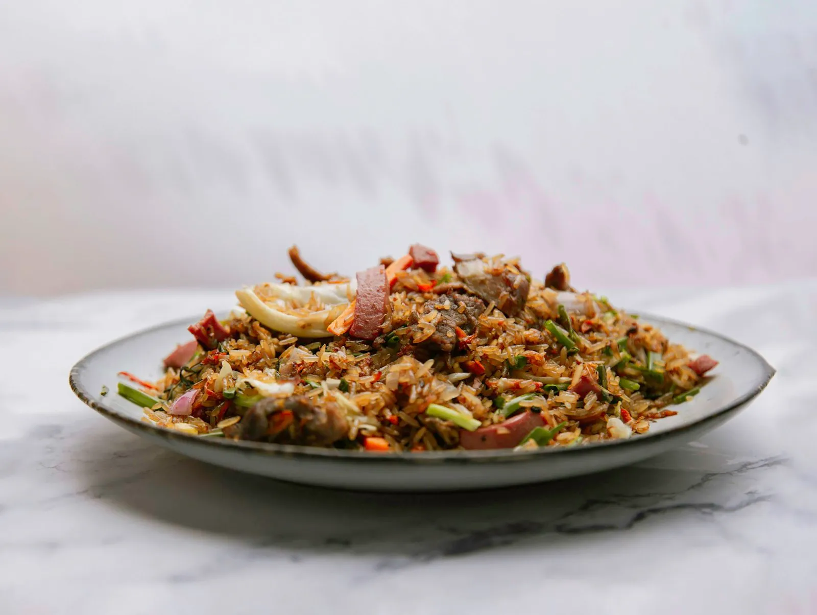 Plate of fried rice mixed with browned meat and shredded cabbage