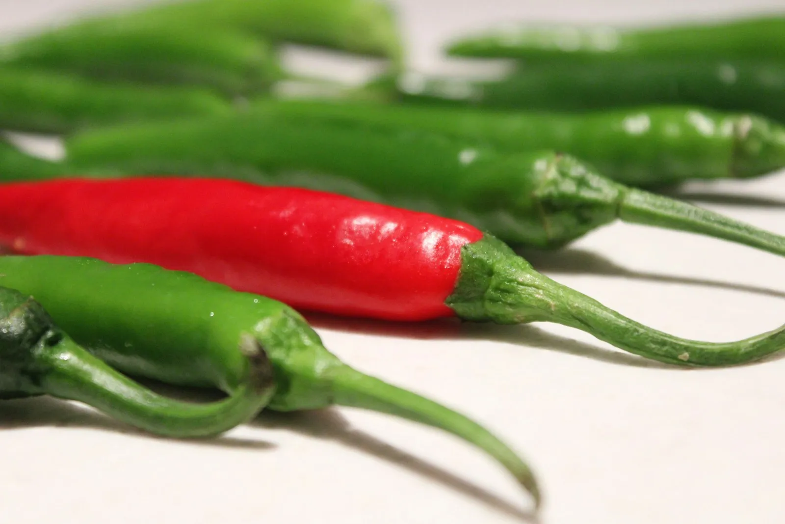 Fresh green and red chillies on a white table