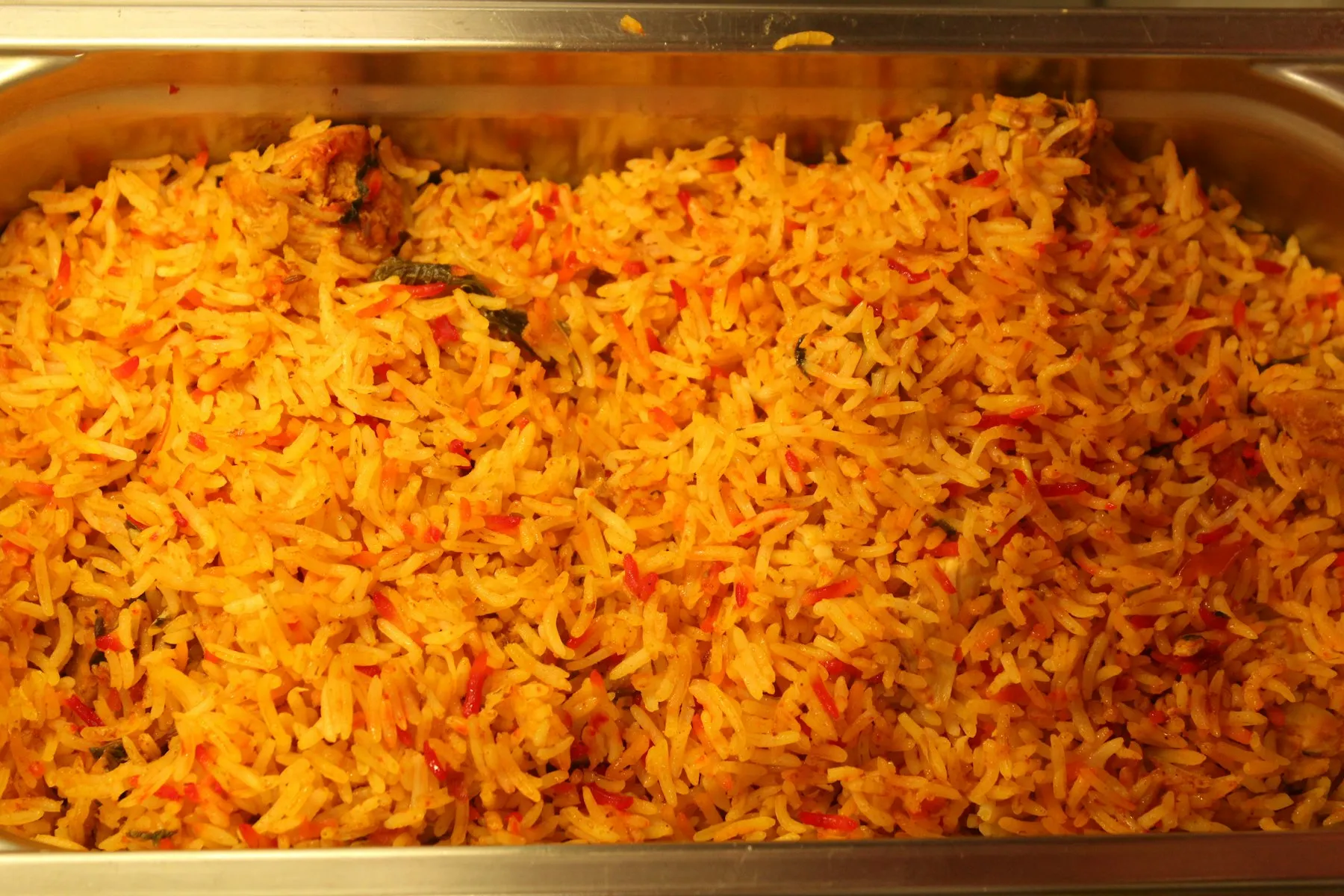 Steel tray filled with orange-red spiced long-grain rice
